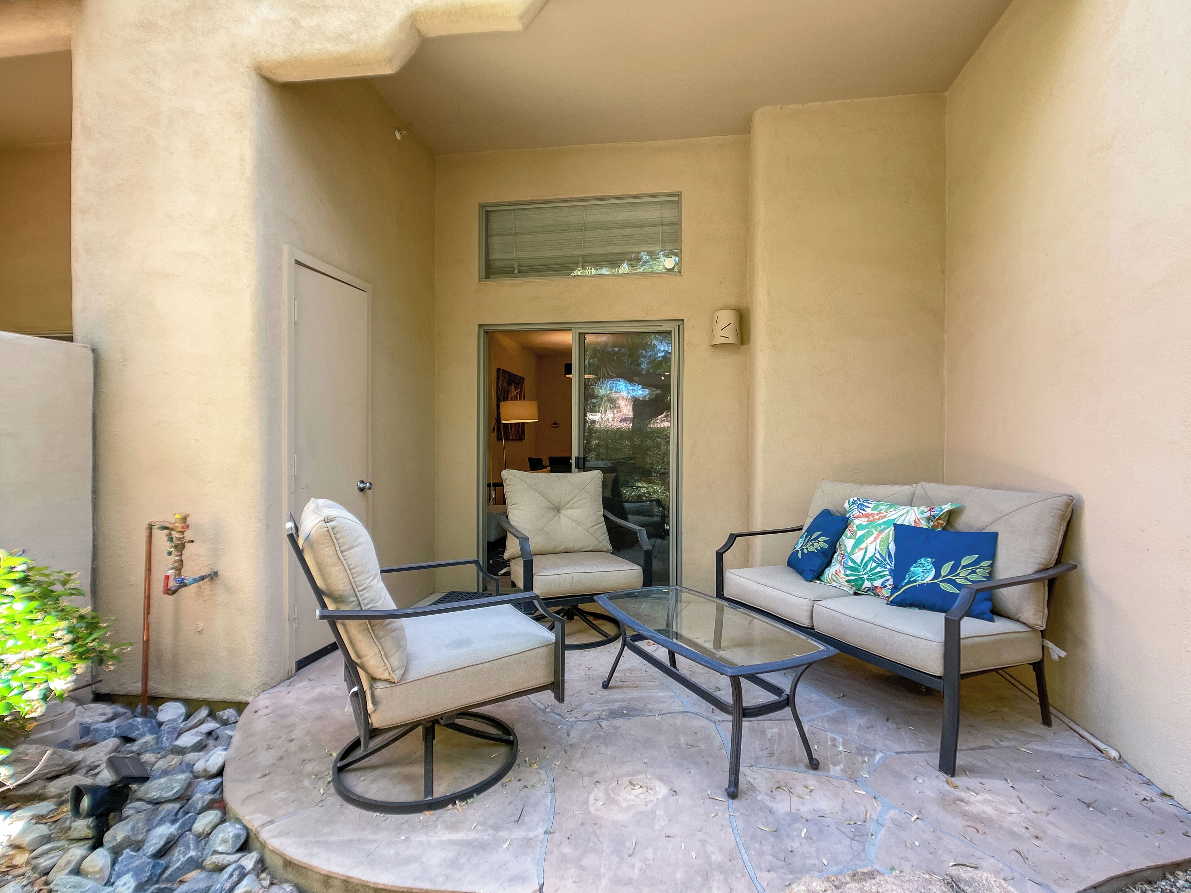 A patio with two chairs, a glass table, and a door leading to an interior space.
