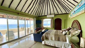 A bedroom with a large bed, a sofa, a view of the beach, and a ceiling with a striped pattern. - Oceanfront Penthouse -4300 Sq Ft, 2 Level -Mi Casa Del Mar (Akumal)