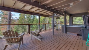 A wooden deck with Adirondack chairs, a hot tub, and a view of trees. - Tahoe Point of View by Tahoe Getaways - Hot Tub + Sauna + Lake Views + Private Beach (Tahoe City)