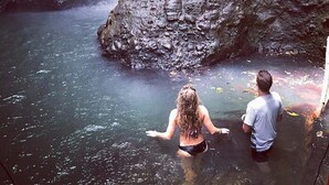 Een waterval in een rotsachtige kloof, met twee personen in het water.