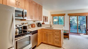 A kitchen with wooden cabinets, a refrigerator, a microwave, a stove, and a sink.