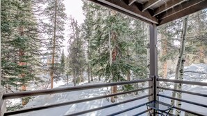 A balcony with metal railings overlooking a snowy forest.