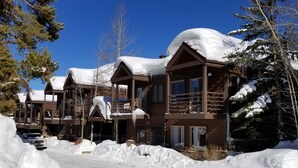 A snow-covered lodge with multiple balconies and a clear blue sky.
