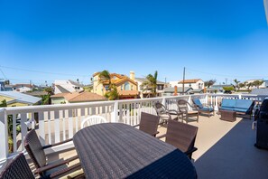 A balcony with wicker furniture, a barbecue grill, and a view of neighboring houses.