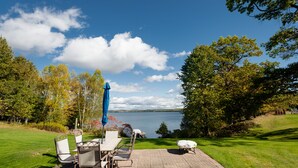 En terrasse med et bord og stole, med udsigt over en sø.