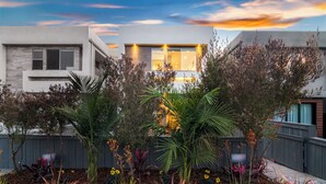Une maison moderne avec un jardin bien entretenu, une clôture en bois et un ciel dégagé.