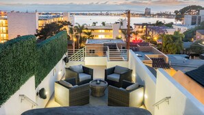 Une terrasse sur le toit avec des sièges extérieurs, une vue sur la ville et un plan d'eau en arrière-plan.