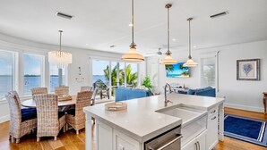 Cozinha moderna com ilha central, armários brancos e iluminação pendente.