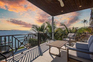 A balcony with a view of the sea, a wooden table, and two chairs.