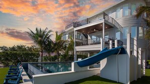 Um edifício com vários andares, piscina, escorrega e varanda.