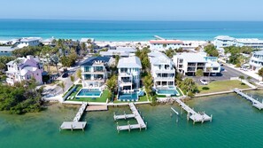 A coastal residential area with multiple two-story houses, a swimming pool, and a dock extending into the water.