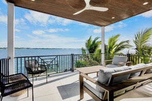Un espace extérieur abrité, aménagé avec une table et des chaises en bois, et offrant une vue sur la mer.