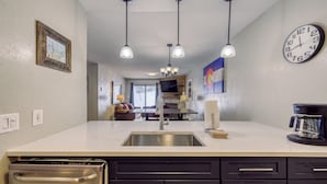 Una cocina moderna con un lavamanos de acero inoxidable, armarios negros e iluminación colgante.