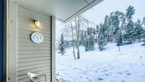 Paisaje nevado con un banco de madera y un reloj en la pared de una casa.