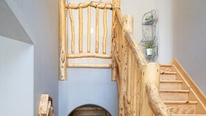 Eine hölzerne Treppe mit rustikalem Design, die zu einer Tür mit kleinem Rundbogen führt.