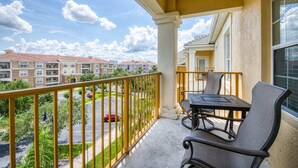 A balcony with a table and chairs, overlooking a parking lot and neighboring buildings. - Top Floor*Balcony*VistaCay Convention Ctr & iDrive (Orlando)