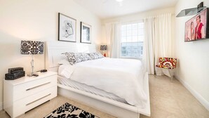 A bedroom with a bed, a nightstand, a lamp, a chair, and a window with curtains. - Top Floor*Balcony*VistaCay Convention Ctr & iDrive (Orlando)