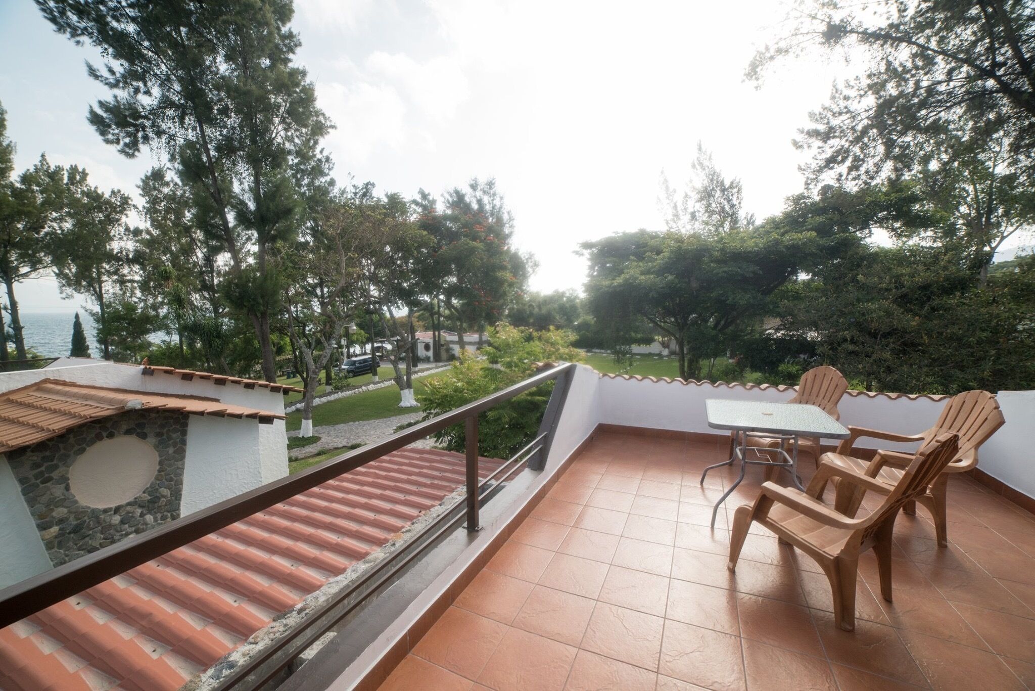 A terrace with a table and chairs, a stone wall, and a view of the sea.