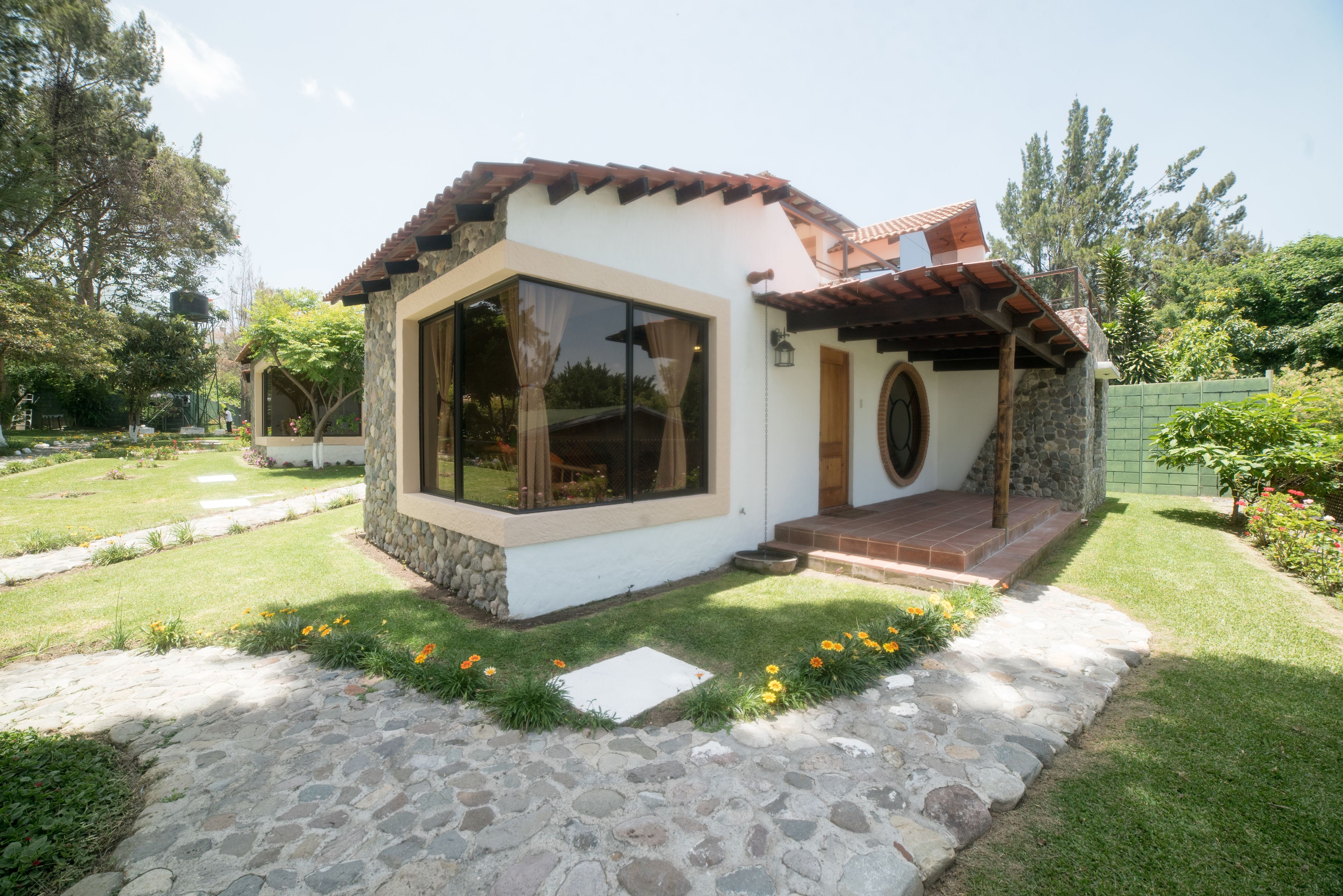 A small, single-story house with a stone facade, large windows, and a tiled roof.