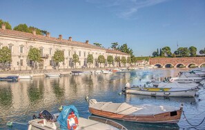 Un canal bordé de bateaux amarrés, un bâtiment historique doté de nombreuses fenêtres et un pont en arrière-plan.