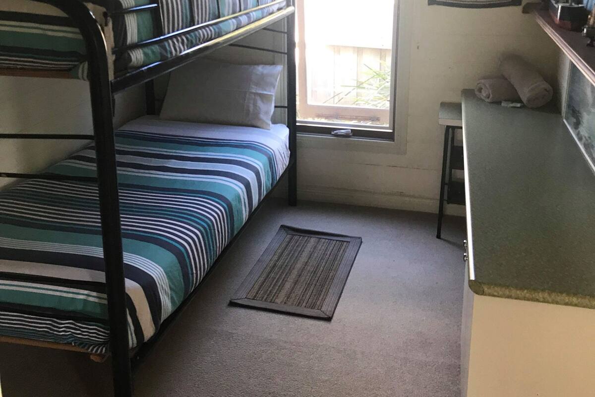 Habitación con literas, un escritorio pequeño y un tablón de anuncios.