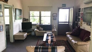 Una sala de estar con sofá, mesa de centro, televisor y ventana que deja entrar luz natural.
