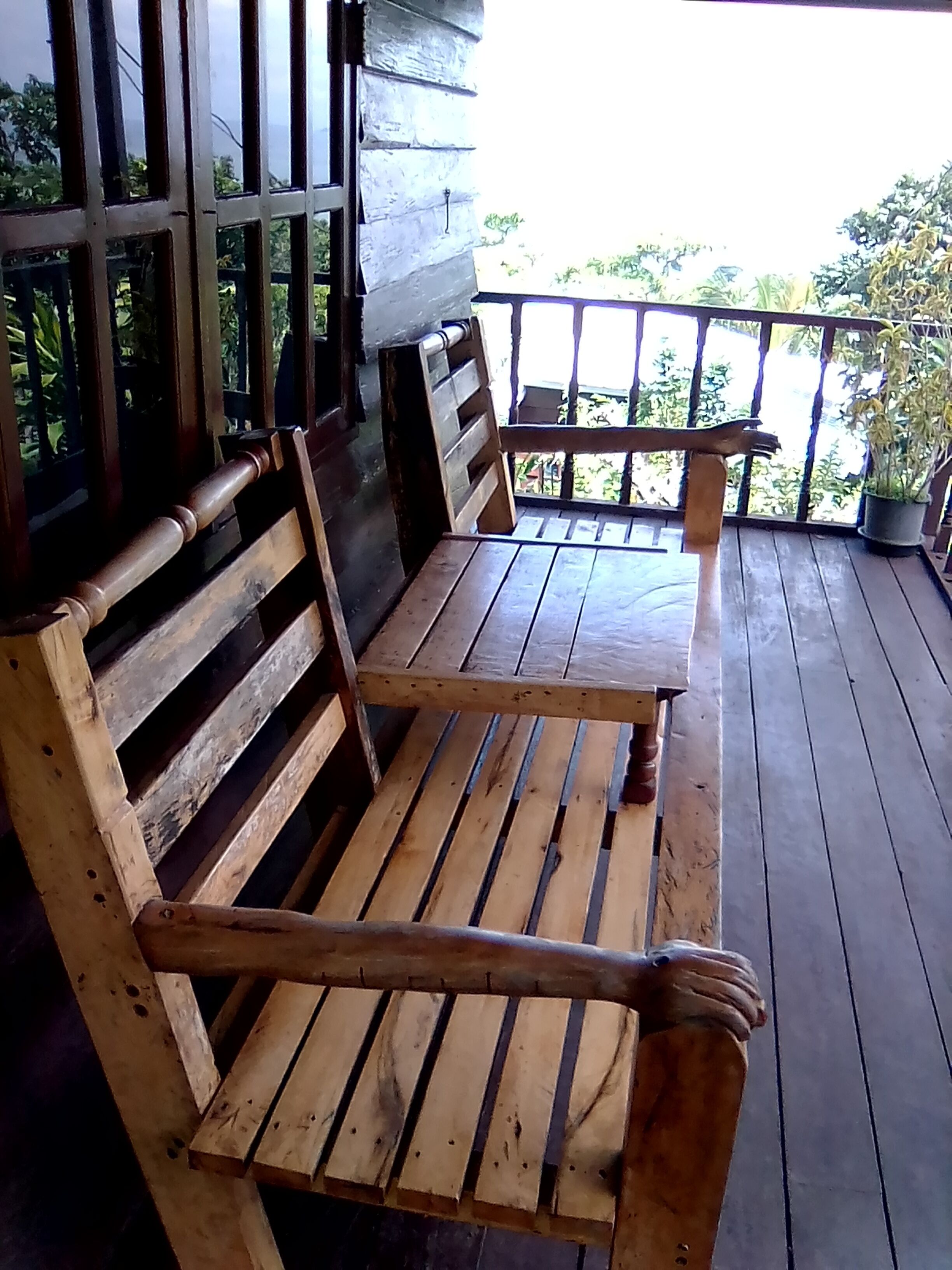 Un banc et une table en bois, installés sur une terrasse en bois dotée d’une rambarde.