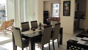 Un coin repas avec une table et des chaises, un téléviseur et un canapé à l’arrière-plan.