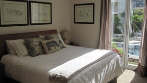 Une chambre d’hôtel avec un grand lit, une table de chevet, une lampe et trois œuvres d’art encadrées accrochées au mur.