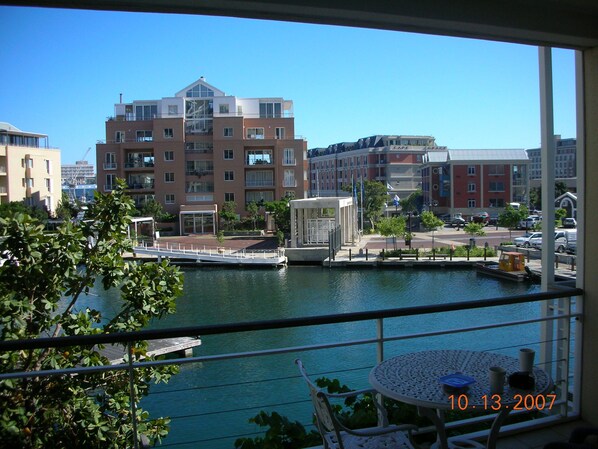 A balcony with a view of a river, buildings, and a date stamp. - Luxurious, Spacious & Secure V&A Waterfront Apt (Cape Town)