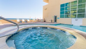 Area con idromassaggio, piscina, poltroncine relax e un edificio con ampie finestre.