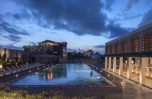 A rooftop pool with lounge chairs, a bar area, and a building with a modern design. - Eastin Ashta Resort Canggu (Canggu)