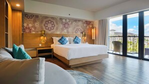 A hotel room with a large bed, a nightstand, a wall with a floral pattern, and a balcony with a view.