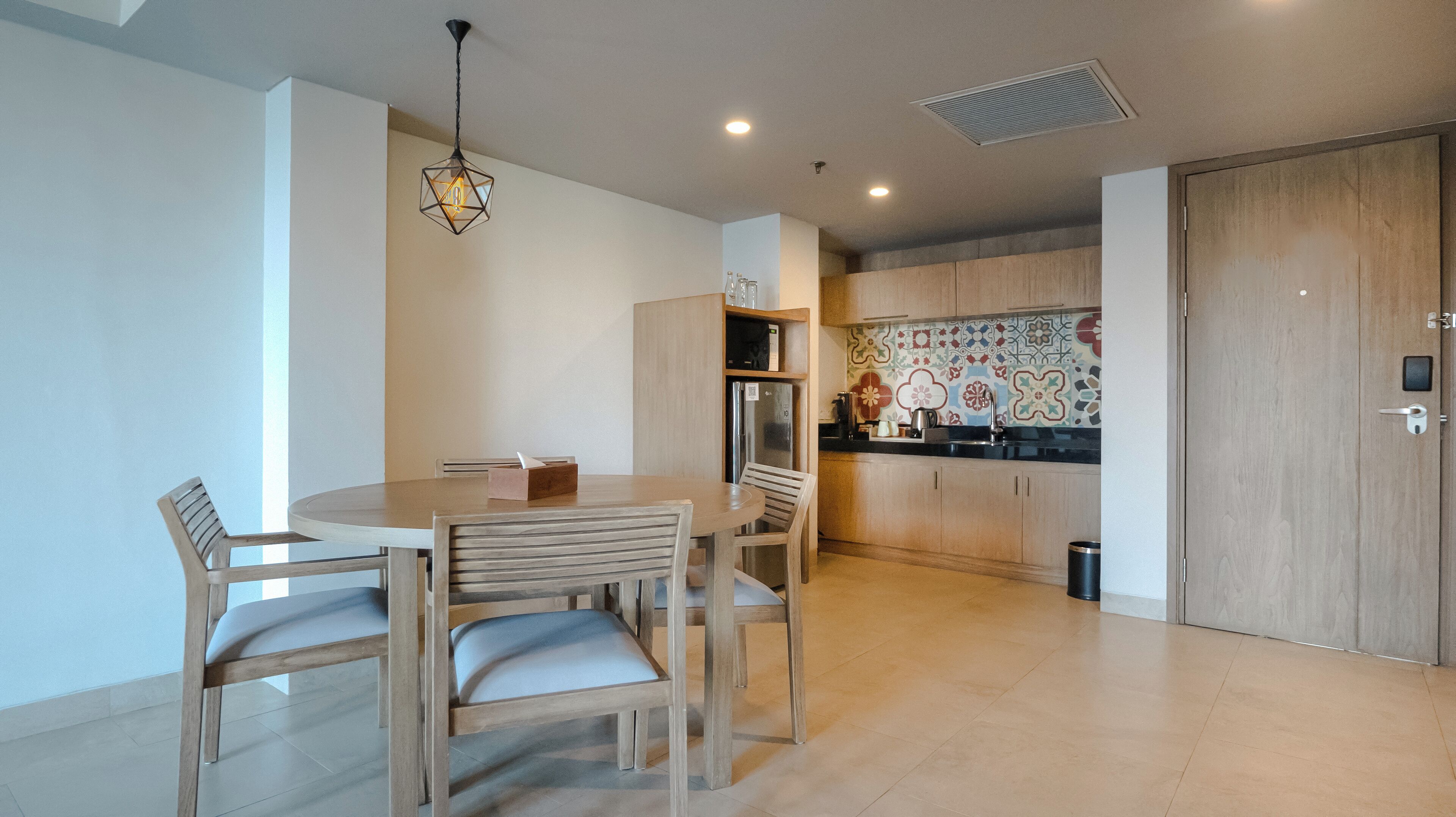 Una cocina moderna con armarios de madera, salpicadero de azulejos y un comedor con una mesa redonda y sillas.