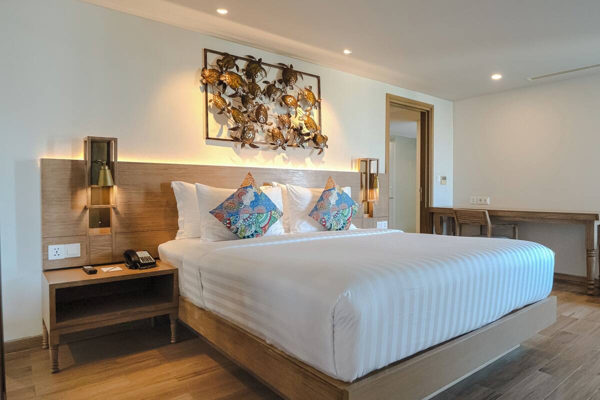 A modern hotel room with a large bed, a desk, and a chair.