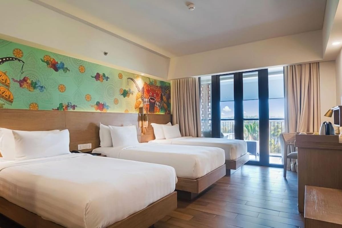 A hotel room with two beds, a large window, and a colorful mural on the wall.