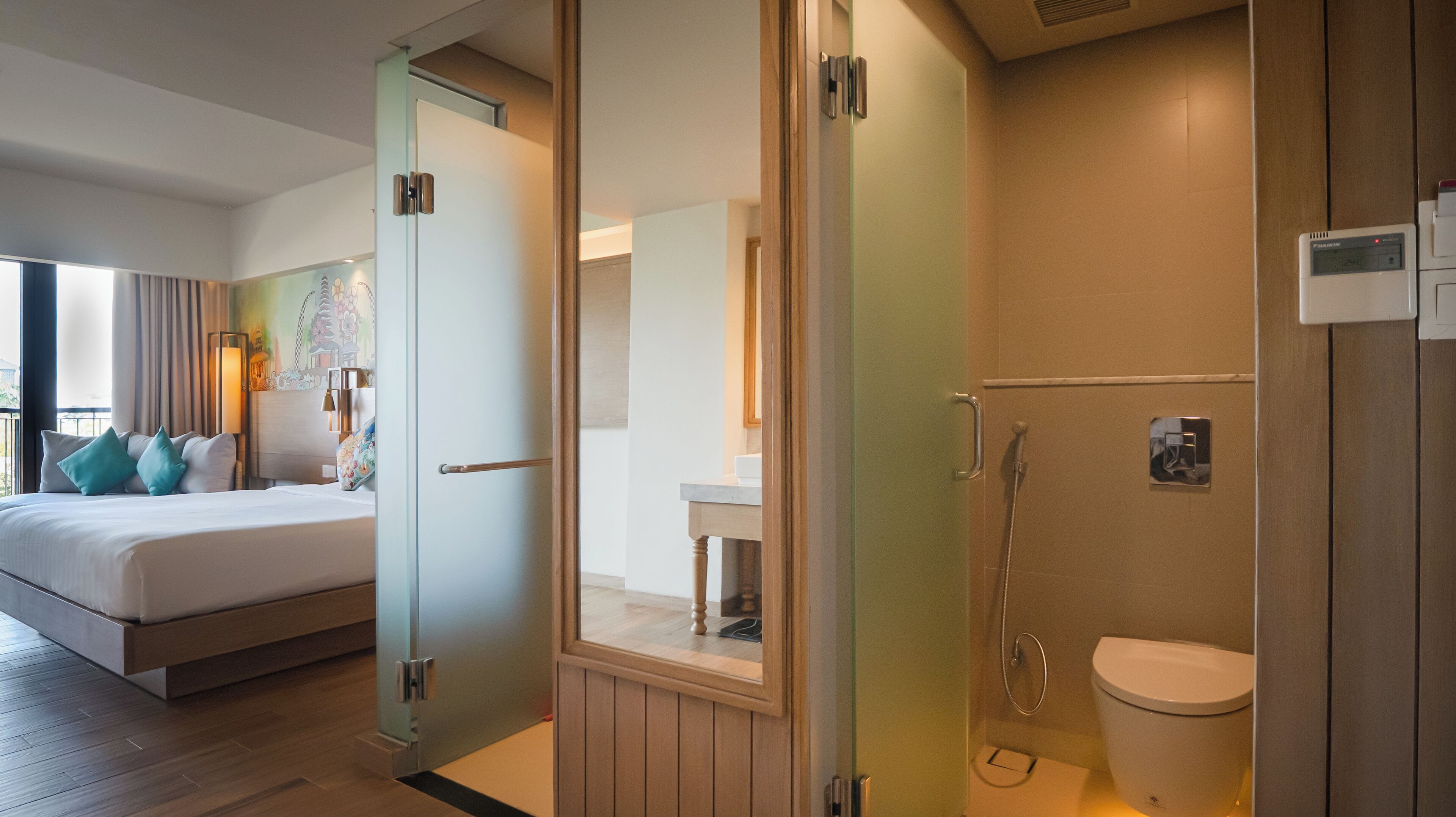 Habitación de hotel con cama, baño con ducha e inodoro, y vista al exterior.