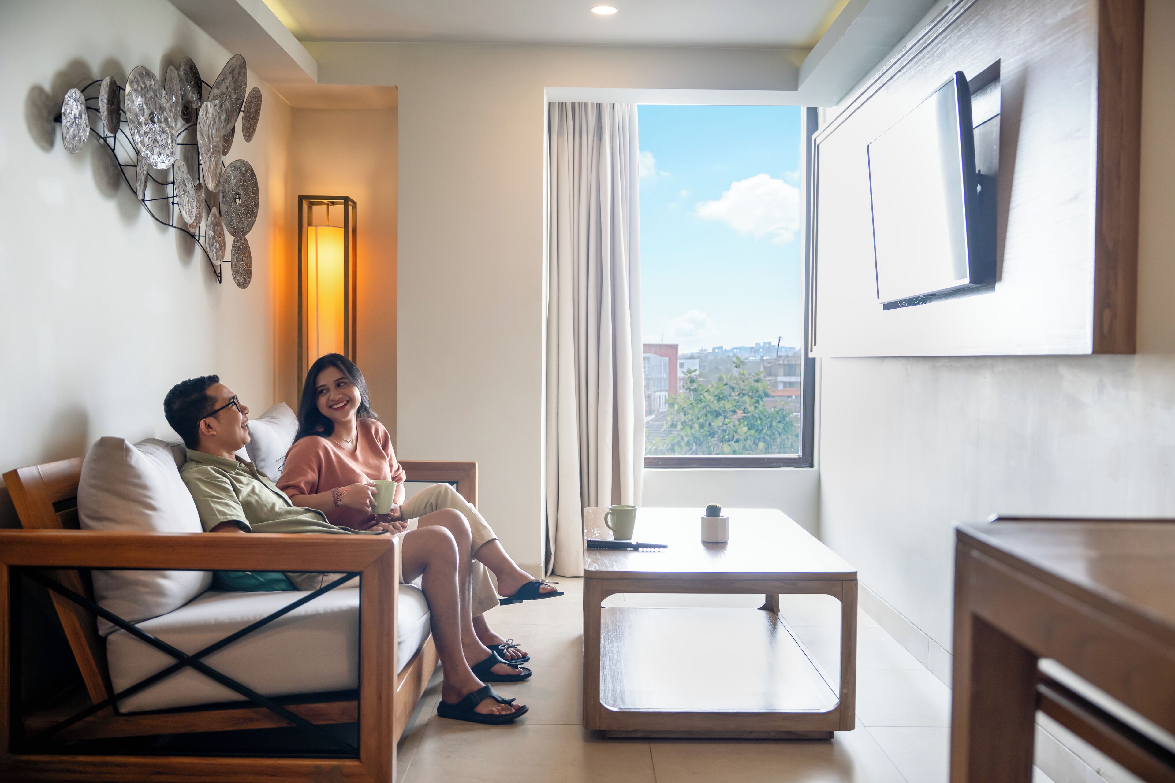 Una sala de estar moderna con sofá, una mesa de centro y un ventanal con vista a la ciudad.