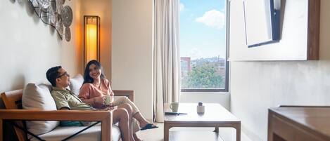 Una sala de estar moderna con sofá, una mesa de centro y un ventanal con vista a la ciudad.