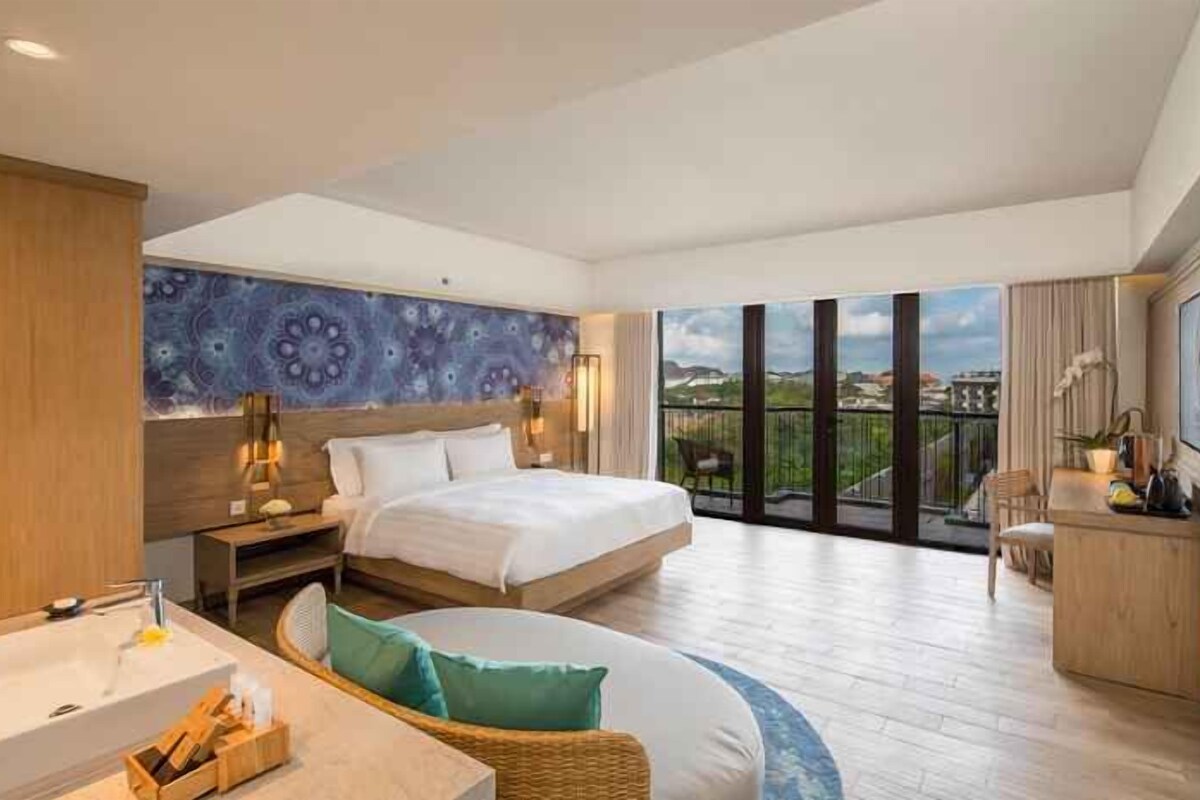 A modern hotel room with a large bed, a balcony, a bathroom with a bathtub, and a dining area.