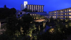 A multi-story hotel with a central courtyard, surrounded by trees and a body of water. - Hotel WELLSEASON Hamanako (Hamamatsu)