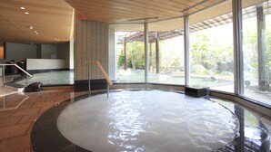 A modern indoor hot tub area with a wooden ceiling, large windows, and a view of the outdoors. - Hotel WELLSEASON Hamanako (Hamamatsu)