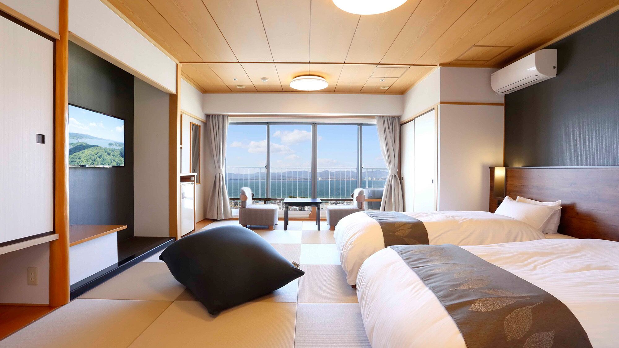 Een hotelkamer met een groot raam, een bed, een bureau en een stoel.