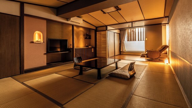 Een traditionele Japanse kamer met tatami vloeren, een lage tafel, een televisie en een schuifdeur naar een andere kamer.