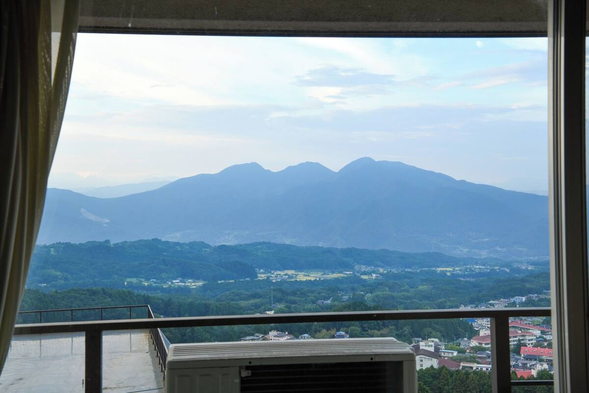 A balcony with a view of distant mountains and a town below.