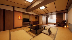 Een traditionele Japanse kamer met tatami vloeren, een lage tafel, een televisie en een schuifdeur naar een balkon.