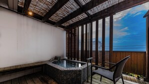 Een hottub met stenen tegels, een houten terras en een stoel.