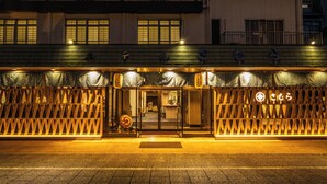 Een gebouw met een traditionele gevel, met een houten lattenwerk en een bord met Japanse tekens.