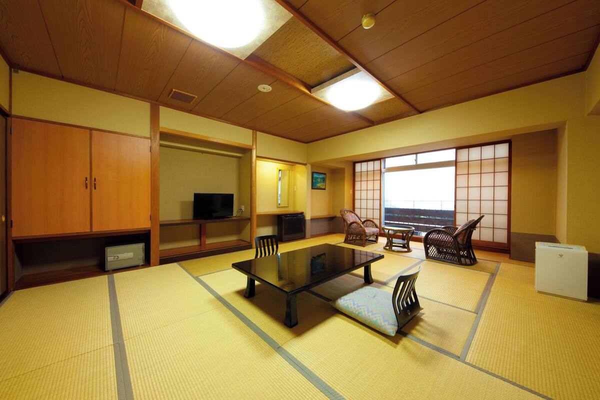 Une pièce de style japonais traditionnel, avec un sol recouvert de tatamis, une table basse et des portes coulissantes.