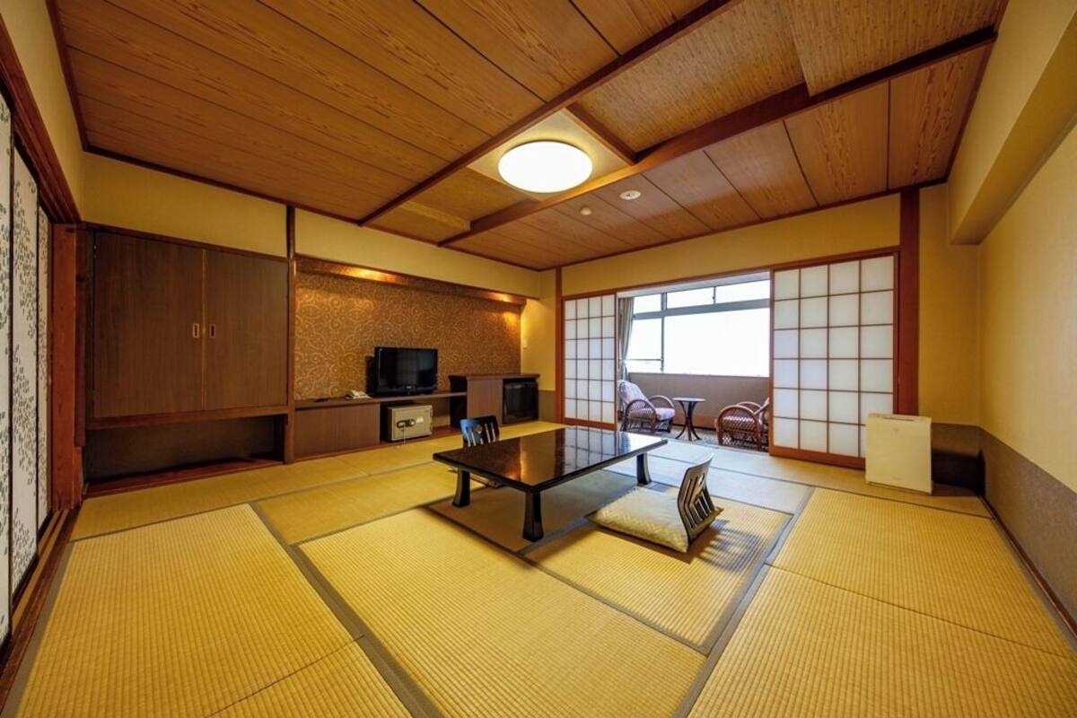 Une pièce de style japonais traditionnel, avec un sol recouvert de tatamis, une table basse et des portes coulissantes.